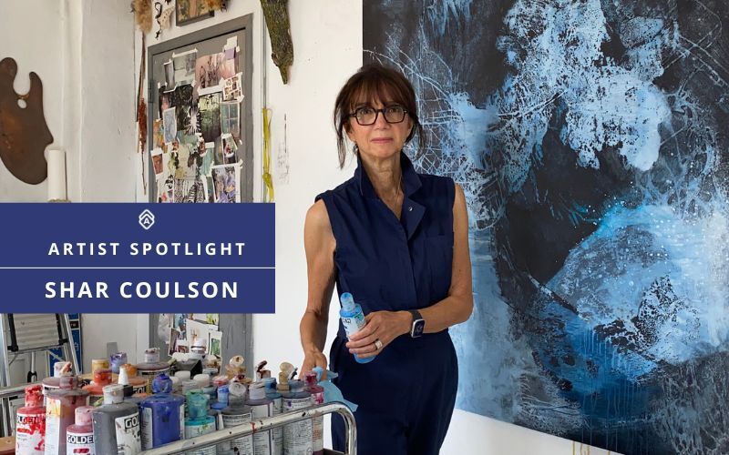 A woman artist in front of her blue painting