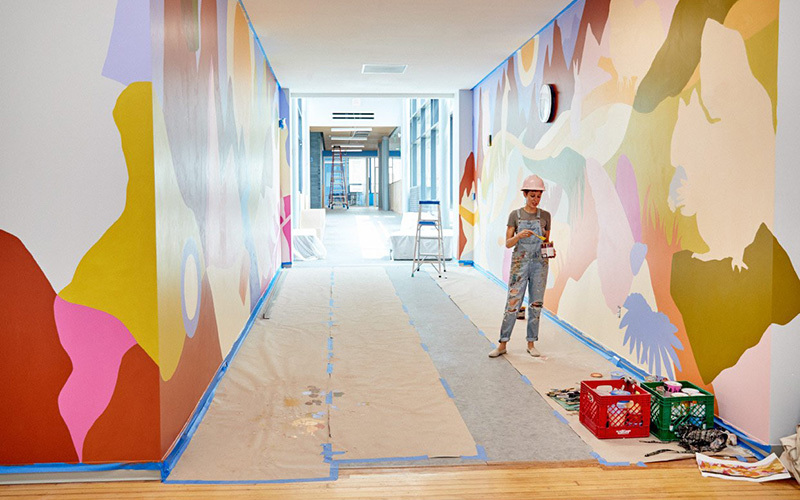 An artist painting a mural in a hallway